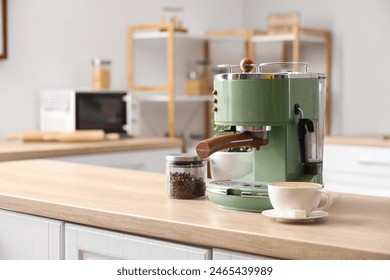 Modern coffee machine, beans and cup of espresso on wooden table in kitchen - Powered by Shutterstock