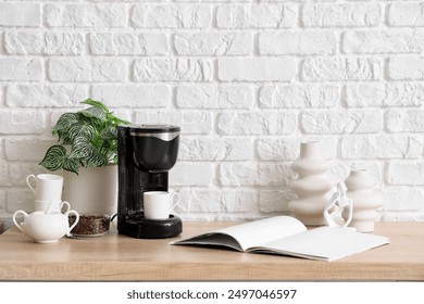 Modern coffee machine with cup, beans and open book on table in kitchen - Powered by Shutterstock