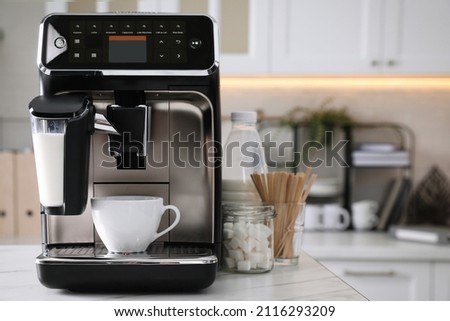 Modern coffee machine with cup in office kitchen, space for text