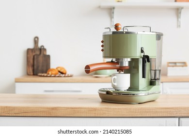 Cafetera moderna con taza en el mostrador en la cocina