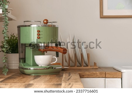 Modern coffee machine with cup on wooden kitchen counter, closeup