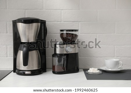Modern coffee maker and grinder on counter in kitchen