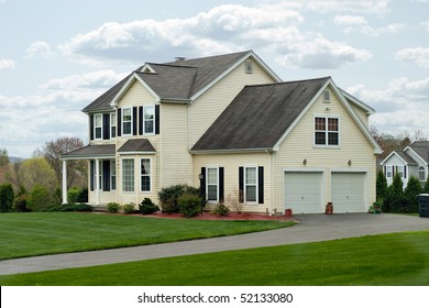 A Modern Colonial Style Residential Suburban Home With A Small Porch And A Two Car Garage.