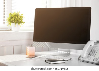 Modern comfortable workplace with computer and window blinds