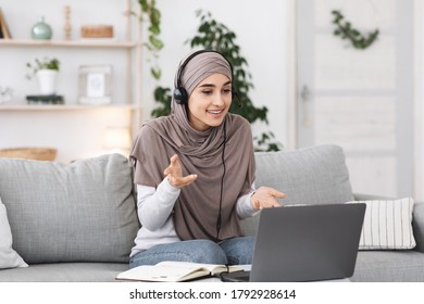 Modern Communication. Cheerful Muslim Woman In Hijab And Headset Talking On Laptop Camera, Having Video Call - Powered by Shutterstock