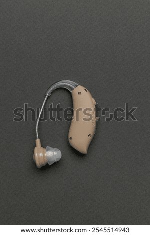 Modern Compact Hearing Aid Device on Gray Background for Enhanced Hearing Solutions