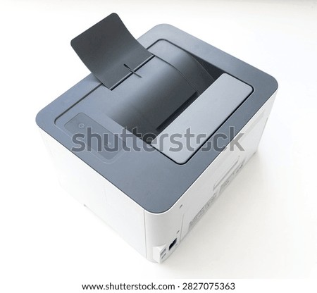 A modern compact laser printer sits on a plain white surface viewed from a high angle