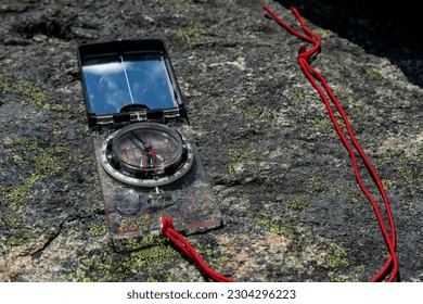 Modern compass for navigating in mountains placed on rocks