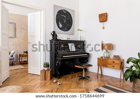 Modern composition of home interior with stylish black piano, design furnitures, plants, decoration, flowers, mock up painitngs and elegant personal accessories in trendy home decor.