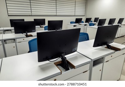 Modern computer classroom with rows of monitors and white desks