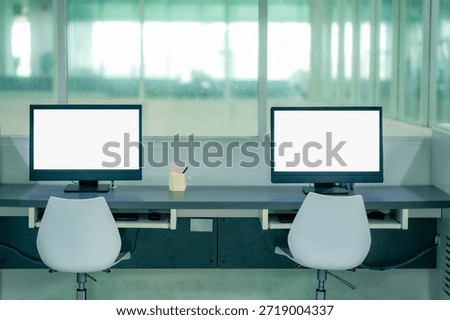 Modern computer desk setup inside library with empty chair screen showing digital study space academic research education technology learning environment.