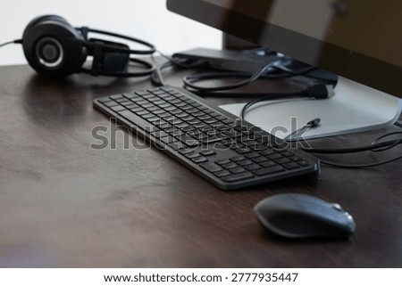 Modern Computer Desk Workspace With Keyboard Mouse Headphones and Monitor on Wooden Surface