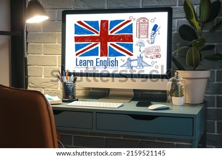 Modern computer with flag of Great Britain and text LEARN ENGLISH on screen at workplace in evening