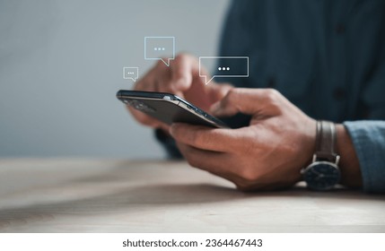 Modern connectivity man on phone types, discussing live chat and social network concepts. Home office with chat box icons portrays digital communication trends. Social media marketing technology - Powered by Shutterstock