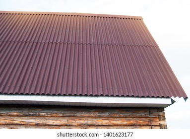 Modern Construction Of The Roof With Red Metal Siding To A Wooden House In The Garden