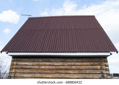 Modern Construction Of The Roof With Red Metal Siding To A Wooden House In The Garden.