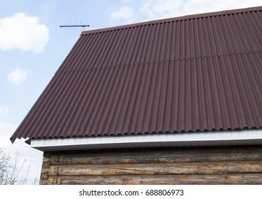 Modern Construction Of The Roof With Red Metal Siding To A Wooden House In The Garden.