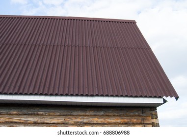 Modern Construction Of The Roof With Red Metal Siding To A Wooden House In The Garden.