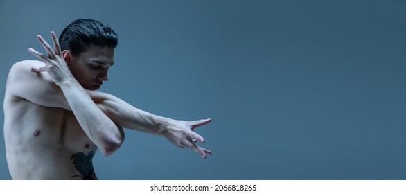 Modern, contemp. One young man, flexible male dancer dancing isolated on old navy studio background. Art, motion, action, flexibility, inspiration concept. Flexible artist. Beauty of male body. Flyer
