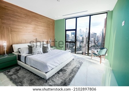 Modern and contemporary bedroom in Melbourne with views of the financial district of the city. Condo or Hotel accommodation. Pale green, maple and gray colors.