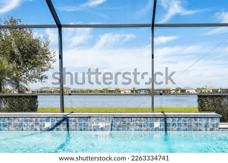 Modern contemporary home screened glass lanai private pool spa with view of tropical lake in Florida with blue water in clean house
