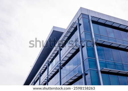 A modern contemporary office building with glass facade on a sunny day no people. Modern facade of glass building. Looking up at business corporate building in downtown