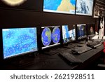A modern control room filled with multiple computer screens displaying weather maps and satellite images. Professionals are analyzing data for research and forecasting.
