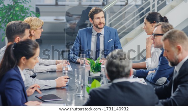 In the Modern Corporate Office Meeting Room:
Diverse Group of Businesspeople, Lawyers, Executives and Members of
the Board of Directors Talking, Negotiating and Working on a
Winning Strategy.