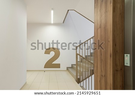 Modern corridor with staircase and elevator in an apartment block with bright colors.