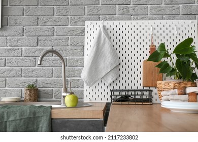 Modern Counter And Pegboard With Kitchen Utensils Near Grey Brick Wall