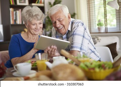 Modern couple of elder people using a touch pad