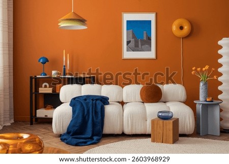 Modern cozy living room with white boucle sofa, orange wall and eclectic decor in bold colors.