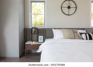 Modern Cozy White Bedroom With Side Table Lamp And Wall Clock.