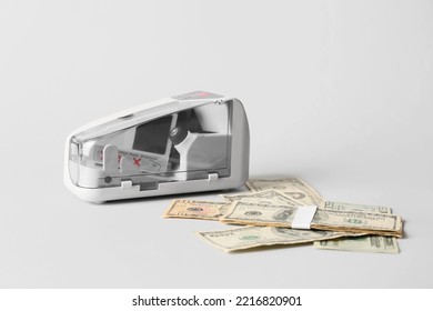 Modern Currency Counting Machine And Dollars On Light Background