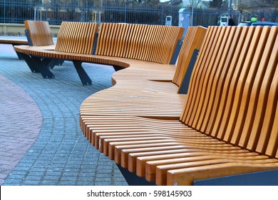 Modern curved s shaped brown wooden bench outdoor