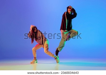 Modern dance aesthetics. Two young people,man and woman dancing contemporary dance over blue background in neon light. Youth culture, motion, lifestyle concept