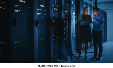 In The Modern Data Center: Engineer And IT Specialist Work With Server Racks, Talking, Doing System Maintenance Check With Laptop Computer. Concept Of Diagnostics Of The Database, Cybersecurity Check