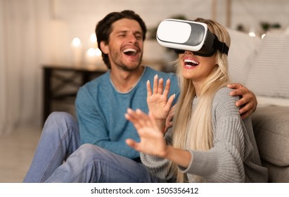 Modern Date. Millennial Couple Using VR Headset Experiencing Virtual Reality At Home At Night.