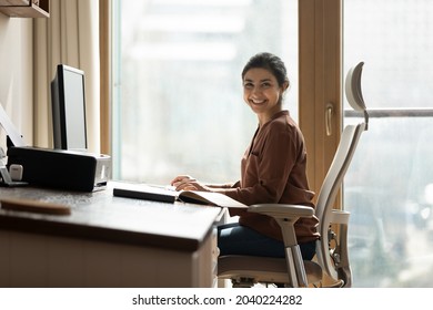 Modern day worker. Portrait of happy biracial business woman freelancer sit by computer at comfy workplace at corporate workspace or at home. Smiling young indian lady office employee look at camera - Powered by Shutterstock