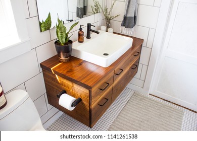 Modern decorated bathroom vanity in a modern white bathroom with natural light and plants.