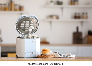 Modern deep fryer and doughnuts on table in kitchen - Shutterstock ID 2018120948