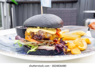 Modern Delicious Black Burger With Meat, Bun, Lettuce, Cheese, Ketchup, French Fries. Funk Food Concept