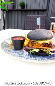 Modern Delicious Black Burger With Meat, Bun, Lettuce, Cheese, Ketchup, French Fries. Funk Food Concept