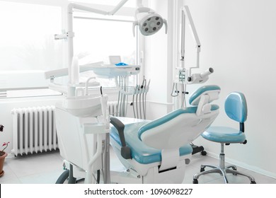 Moderne Zahnarztklinik, Zahnarztstuhl und anderes Zubehör, das von Zahnärzten in blauem medizinischem Licht verwendet wird. Zahnarzt, ist ein Chirurg, der sich auf Zahnmedizin und Behandlung von Erkrankungen der Mundhöhle spezialisiert hat.