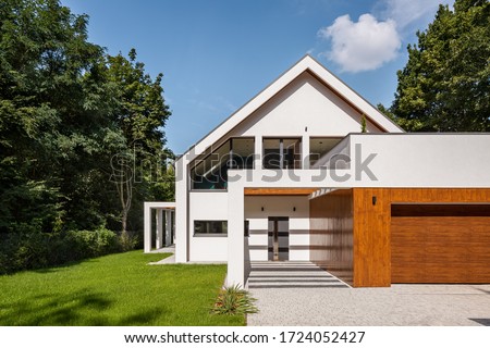 Modern designed white house with big garden and garage, exterior view