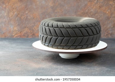 Modern Designer Chocolate Cake In The Shape Of A Car Tire As A Gift To A Motorist Or Racer - The Cake Consist Of Mousse And Covered Dark Chocolate On A Stand - Copy Space And Side View