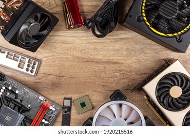 Modern Desktop Computer Hardware Components On Wood Desk Table Background. Circle Shaped Out Of Pc Parts Like Cpu Fan Cooler Motherboard Ram Graphics Card Ssd And Power Supply Wood Technology Concept.