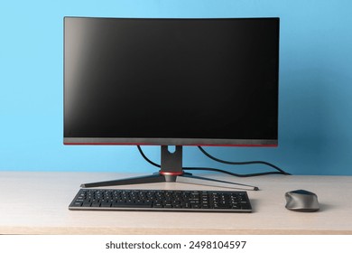 Modern Desktop Setup with Computer Monitor, Keyboard, and Mouse on Wooden Desk Against Blue Background