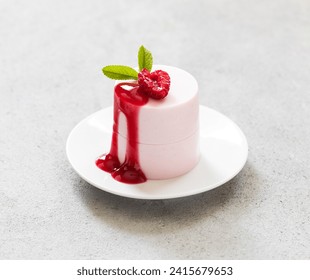 Modern dessert. Raspberry cream pudding of cylindrical shape with raspberry sauce. On a plate. Light gray background. Valentine's Day. Close up - Powered by Shutterstock