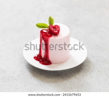 Modern dessert. Raspberry cream pudding of cylindrical shape with raspberry sauce. On a plate. Light gray background. Valentine's Day. Close up